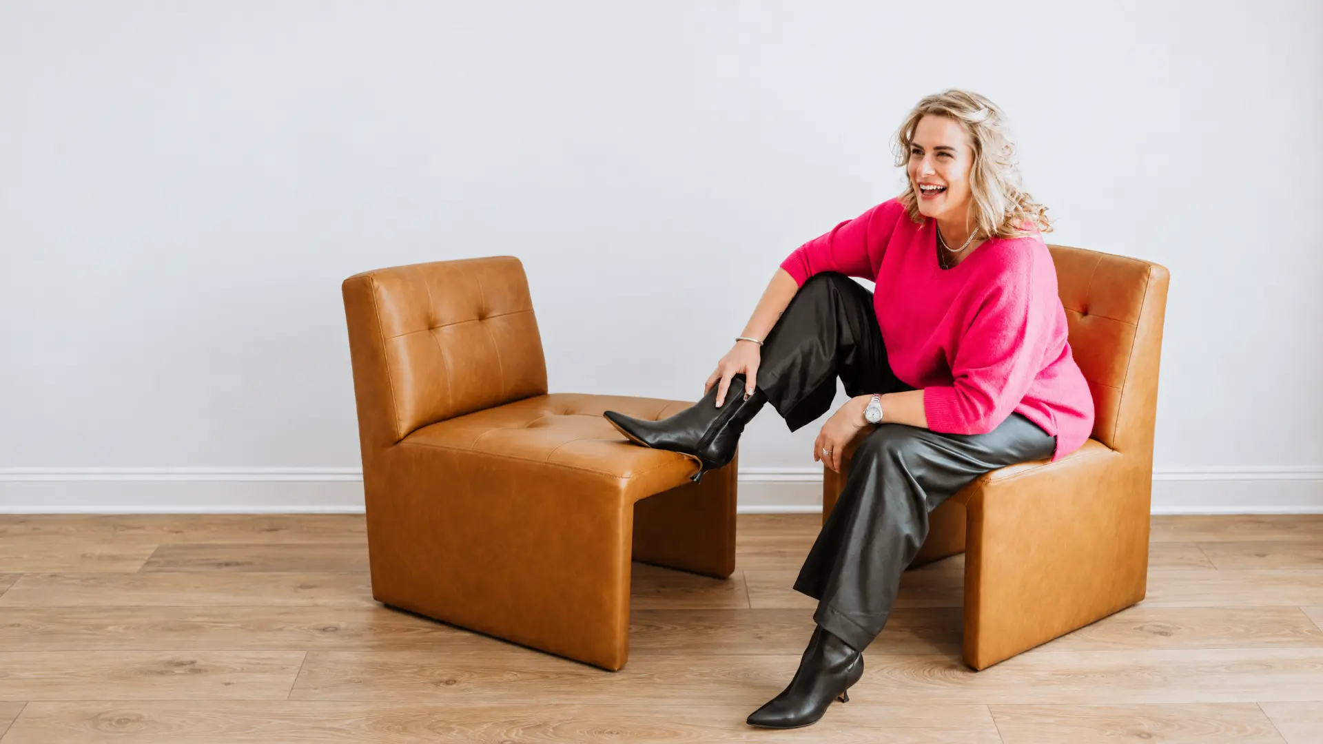 Val laughing in a leather chair with her feet up