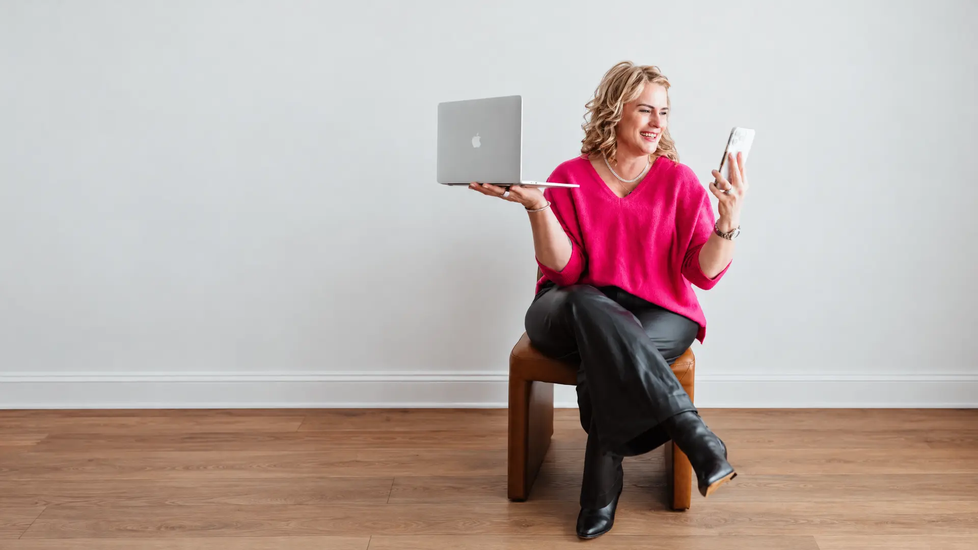 Val Gallagher balancing an open laptop on one hand while reading her phone